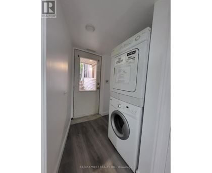 A white dryer is in a small room with a doorway leading to a hallway.