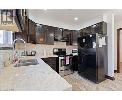 A black refrigerator in a kitchen with wooden cabinets.
