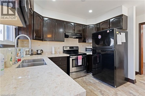 A black refrigerator in a kitchen with wooden cabinets.