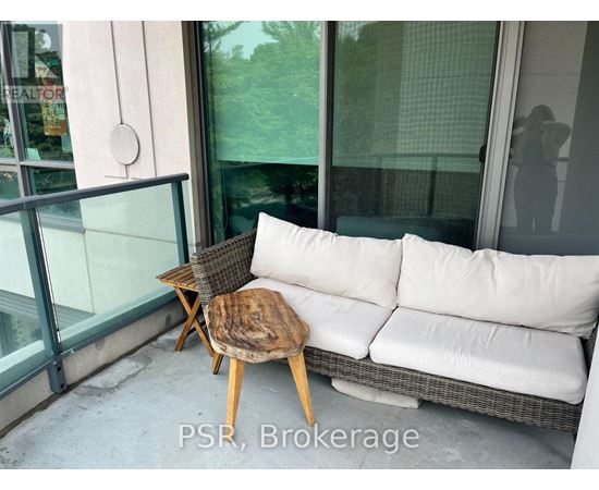 A white couch with a wooden stool in front of a glass door.