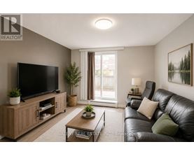 A living room with a black leather couch, a flat screen TV, and a wooden cabinet.