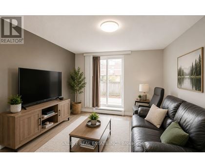 A living room with a black leather couch, a flat screen TV, and a wooden cabinet.