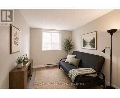 A living room with a black couch and a lamp.