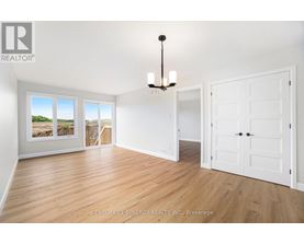 A Synergy Realty Inc. brokerage logo is displayed on a wall in a spacious room with hardwood floors and white walls.