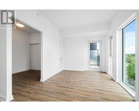 A room with wooden floors and white walls, with a doorway leading to another room.
