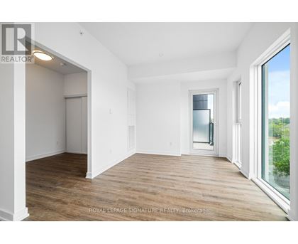 A room with wooden floors and white walls, with a doorway leading to another room.