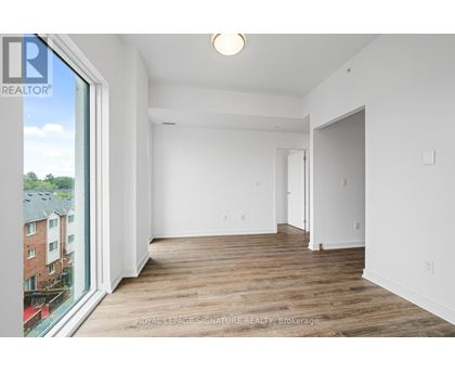 A white room with a wooden floor and a large window.