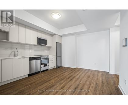 A kitchen with white cabinets and a wooden floor.