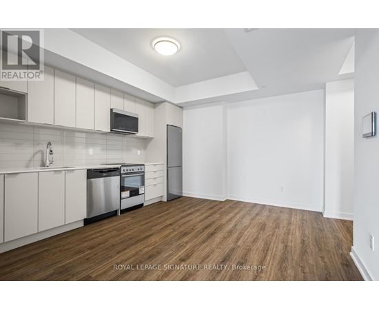 A kitchen with white cabinets and a wooden floor.