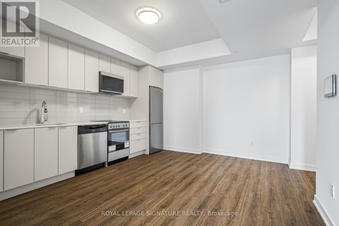 A kitchen with white cabinets and a wooden floor.
