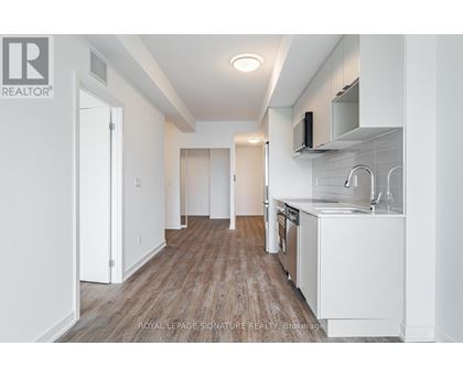 A kitchen with white cabinets and a wooden floor.