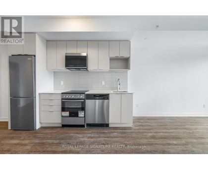 A kitchen with a refrigerator, oven, and microwave.