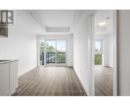 A spacious room with wooden flooring and white walls, with a sliding glass door leading to a balcony.