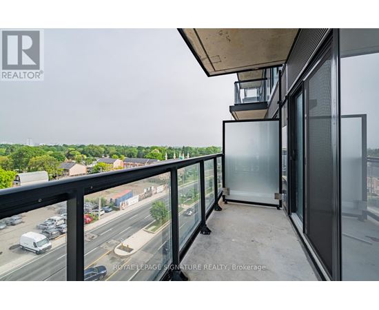 A balcony with a glass door and a view of a highway and trees.
