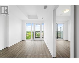 A spacious room with wooden floors and large windows overlooking a garden.