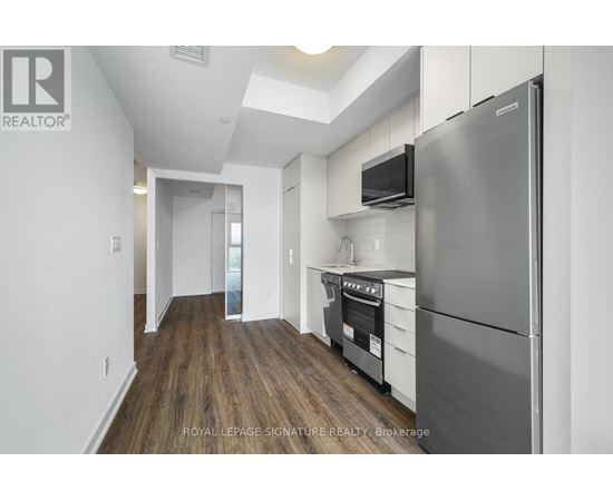 A kitchen with a refrigerator, oven, and microwave.