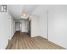 A spacious room with wooden flooring and white walls, with a door on the right side.