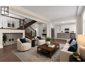 A modern living room with a staircase and a kitchen in the background.