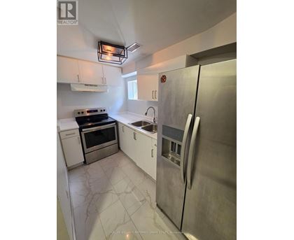 A kitchen with a stainless steel refrigerator, oven, and sink.