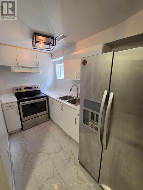A kitchen with a stainless steel refrigerator, oven, and sink.
