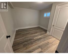 A room with wooden flooring and a door on the right side.