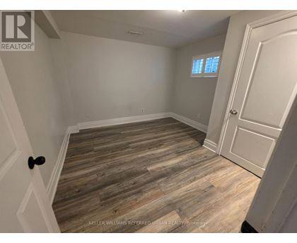 A room with wooden flooring and a door on the right side.