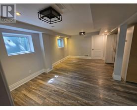 A spacious room with wooden flooring and a ceiling light fixture.