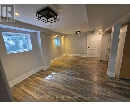 A spacious room with wooden flooring and a ceiling light fixture.