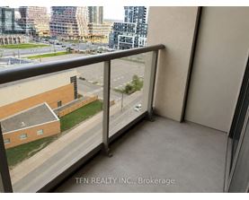 A balcony with a view of a parking lot and buildings.