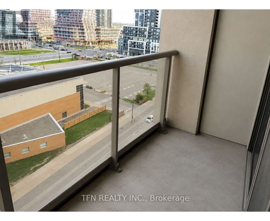 A balcony with a view of a parking lot and buildings.