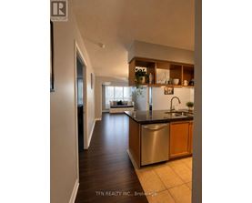A modern kitchen with dark wood floors and stainless steel appliances.