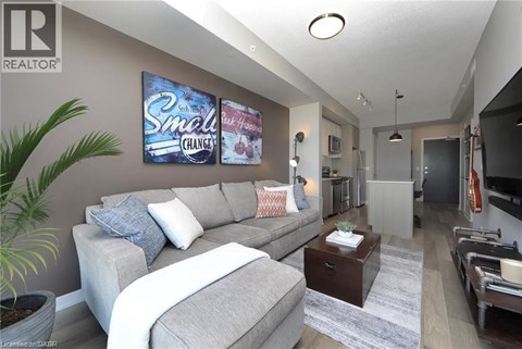 A living room with a grey couch and a poster on the wall.