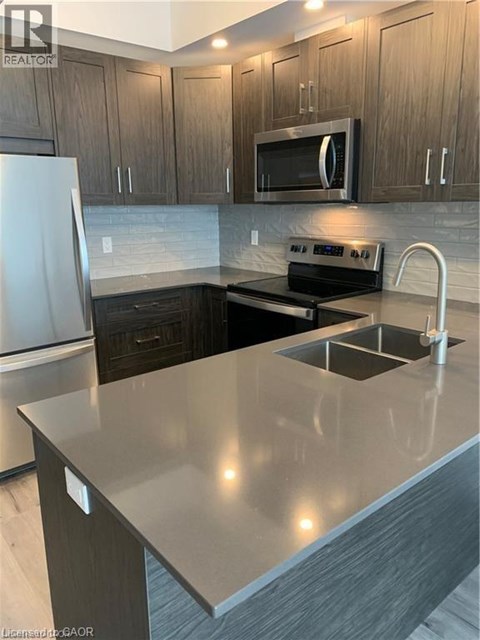 A modern kitchen with a stainless steel refrigerator and a microwave above the stove.