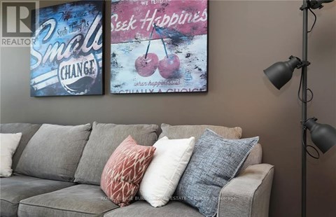 A living room with a grey couch and two posters on the wall.