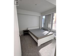 A bedroom with a bed, nightstand, and window.