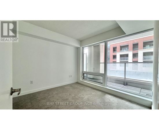 A room with a large window and a view of a red building across the street.