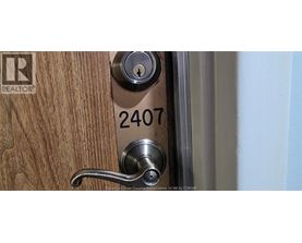 A door handle with a lock and a number 2407 on the door.