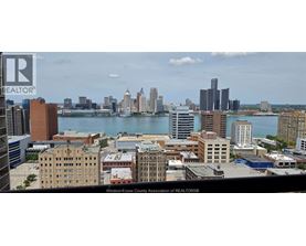 A cityscape with a body of water in the foreground and buildings of varying heights in the background.
