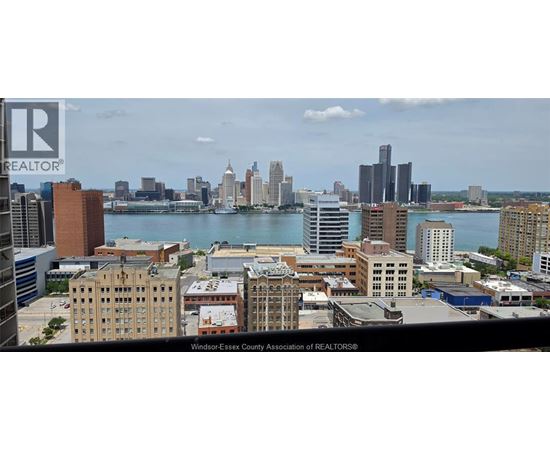 A cityscape with a body of water in the foreground and buildings of varying heights in the background.