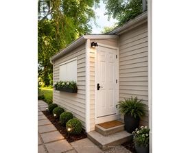 A small white shed with a black door and a black planter box on the side.