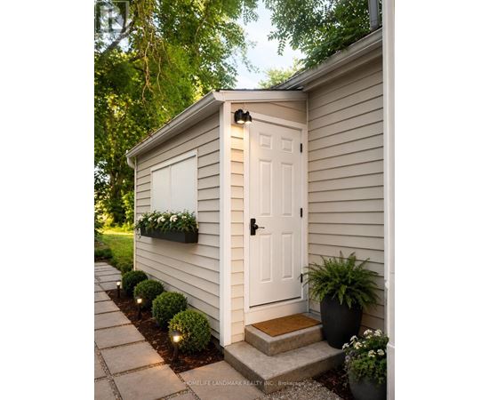 A small white shed with a black door and a black planter box on the side.