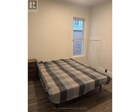 A bedroom with a bed, nightstand, and window.