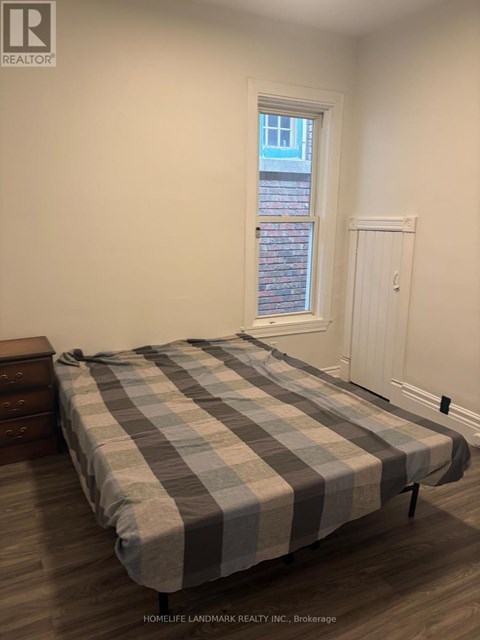 A bedroom with a bed, nightstand, and window.