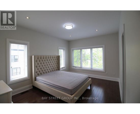 A bedroom with a large bed and a window with blinds.