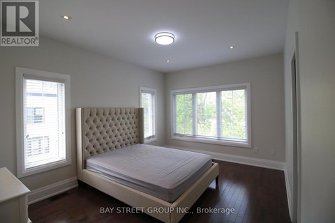 A bedroom with a large bed and a window with blinds.