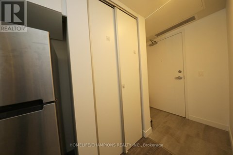 A kitchen area with a refrigerator and a door leading to another room.