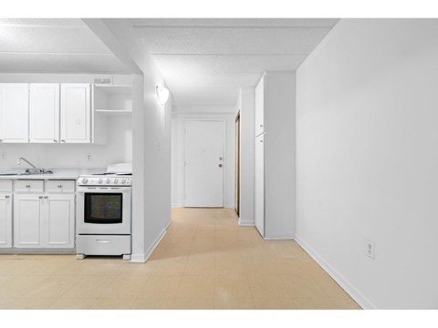 A white kitchen with a stove top oven and a white fridge.