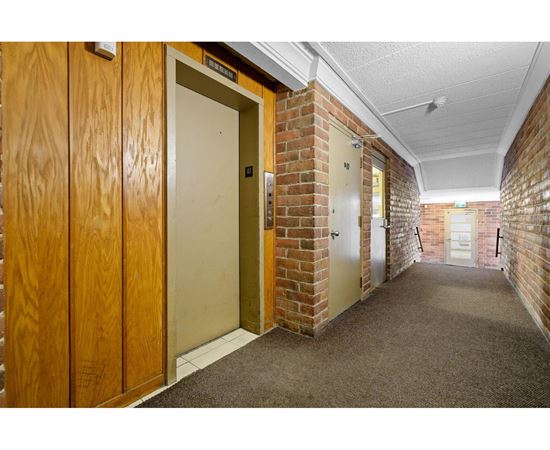 A hallway with wooden doors and brick walls.