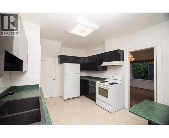 A kitchen with white appliances and a green counter.