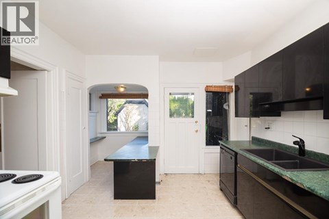 A kitchen with a black counter top and a white stove top.